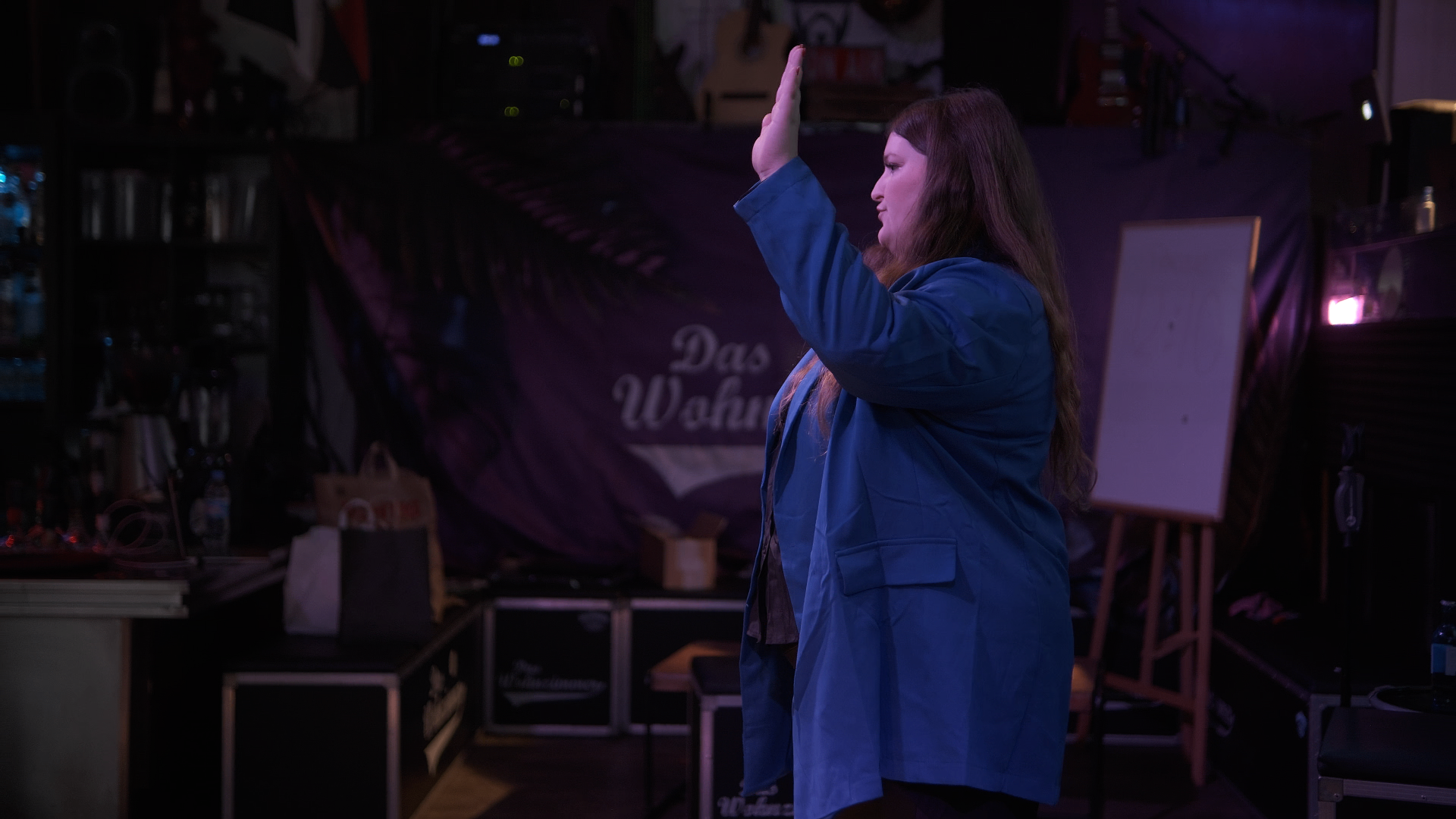 Stella Pollak im blauen Blazer auf der Bühne im Wohnzimmer-Club